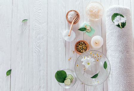 Spa essentials including candle, salt, herbs and white clay on wooden backgroundの写真素材