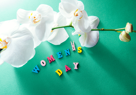 Women's day greeting card. Lettering with white orchid on green backgroundの写真素材