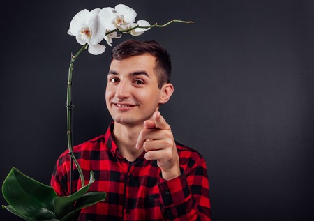 Young handsome man prepared orchid as a gift boxes for women's day on black backgroundの写真素材