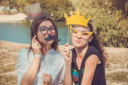 Two young women posing using photo booth props outdoorsの写真素材