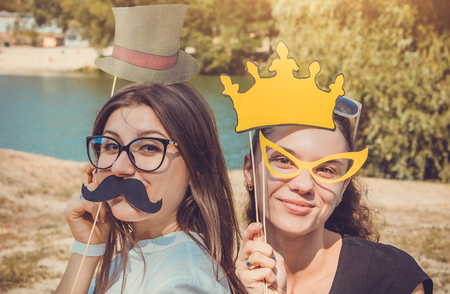 Two young women posing using photo booth props outdoorsの写真素材