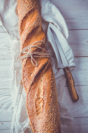 Freshly baked baguette in cloth on wooden tableの写真素材