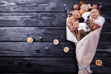 Sweet eatable bouquet wrapped in paper on black wooden backgroundの写真素材