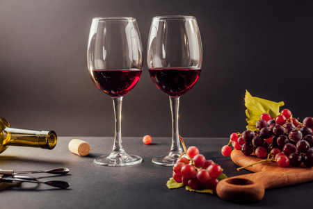 Two glasses of wine with grapes on black backgroundの写真素材