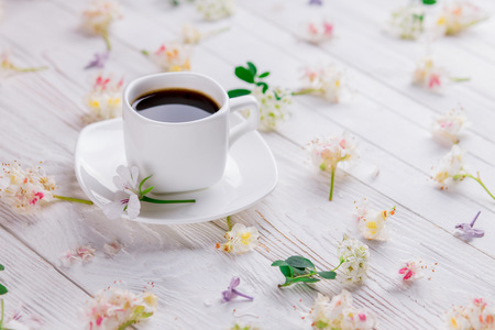 Cup of coffee surrounded with flowers on white backgroundの写真素材