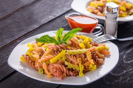 Colourful pasta with sauce on black wooden tableの写真素材