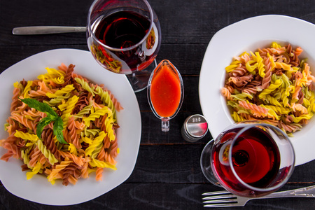 Colourful pasta with wine on black wooden tableの写真素材