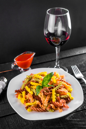 Colourful pasta with wine on black wooden tableの写真素材