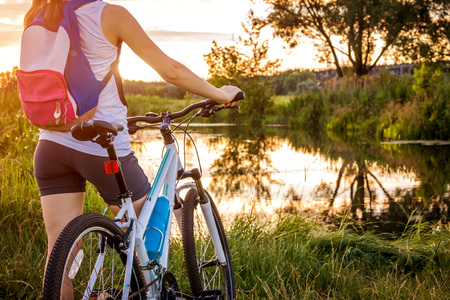 Bicyclist looking at the river at sunsetの写真素材