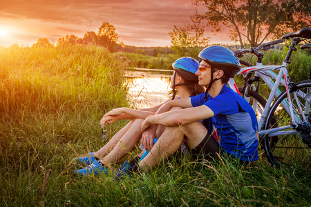 Couple of bicyclists having rest by the riverの写真素材