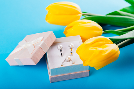 Set of silver ring and earrings with pearls in the gift box with yellow tulips. Present for a Mothers Dayの写真素材