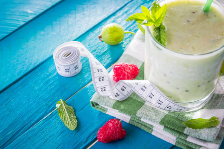 Fruity smoothie with gooseberry and raspberry on blue tableの写真素材