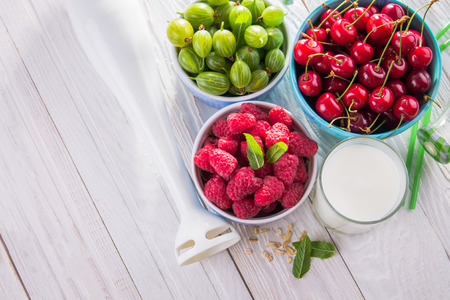 Cooking fruity smoothie with berries using a blender on wooden tableの写真素材