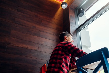 Young handsome man enjoys coffee in the cafe in front of the windowの写真素材
