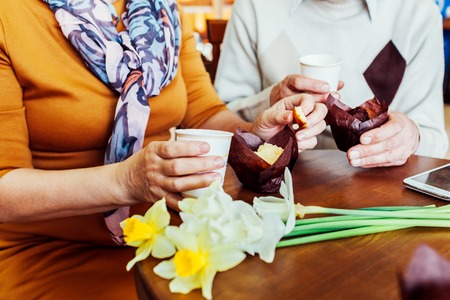 Senior couple holds hands in the cafe drinking coffee. Celebrating anniversary. Closeup.の写真素材