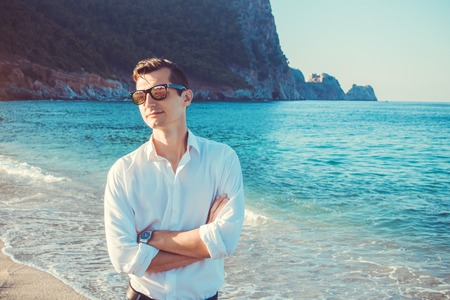 Young businessman at the beach surrounded by mountainsの写真素材