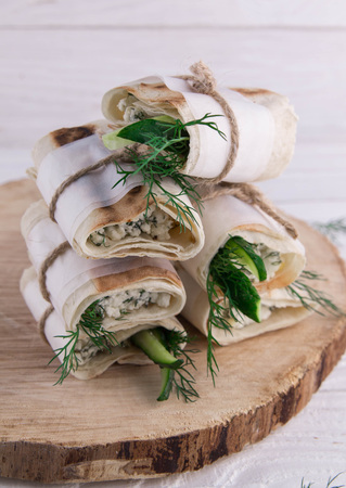 Tortilla wraps with cottage cheese, dill and cucumber on wooden background. Healthy eating concept. Organic foodの写真素材