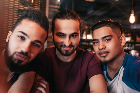 Group of arabian friends taking selfie in lounge bar. Mixed race best friends having good time together in cafeの写真素材
