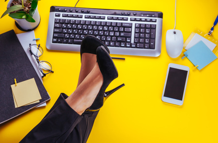 Female office worker is having a rest. Woman put her legs on tableの写真素材