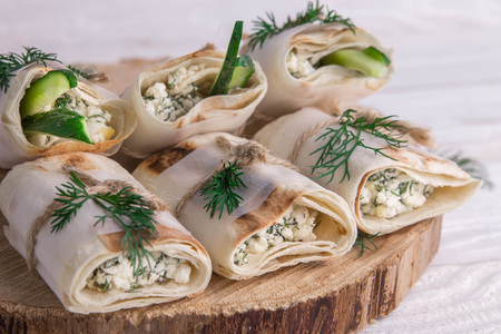 Tortilla wraps with cottage cheese, dill and cucumber on wooden background. Healthy organic food concept. Vegan foodの写真素材