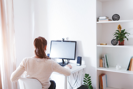 Workspace of business woman. Woman works on computer in light sunny room . Modern design with white furniture and new technologies.の写真素材