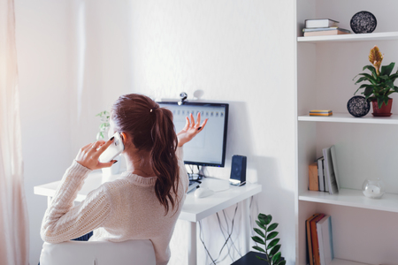 Workspace of woman freelancer. Woman works on computer at home and talks on the phone. Working process conceptの写真素材