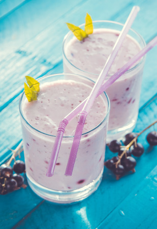 Fruity smoothie in glasses with black currant on blue wooden background. Healthy eating. Organic food.の写真素材