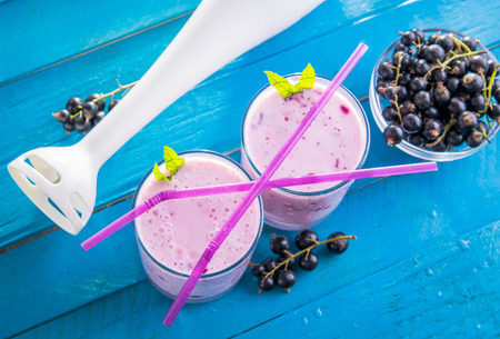 Fruity smoothie in glasses with black currant on blue wooden background. Healthy eating. Organic food.の写真素材