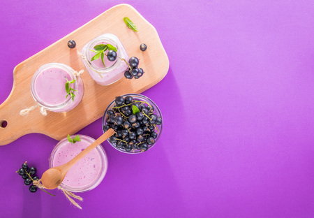 Fruity smoothie in glasses with black currant on purple background. Healthy eating. Organic food.の写真素材