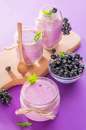 Fruity smoothie in glasses with black currant on purple background. Healthy eating. Organic food.の写真素材