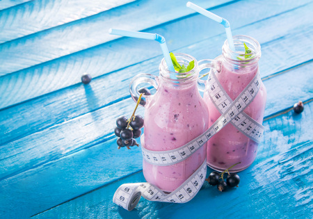 Fruity smoothie in glasses with black currant on blue wooden background. Diet concept. Healthy eating. Organic food.の写真素材