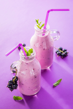 Fruity smoothie in glasses with black currant on purple background. Healthy eating. Organic food.の写真素材