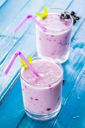 Fruity smoothie in glasses with black currant on blue wooden background. Healthy eating. Organic food.の写真素材