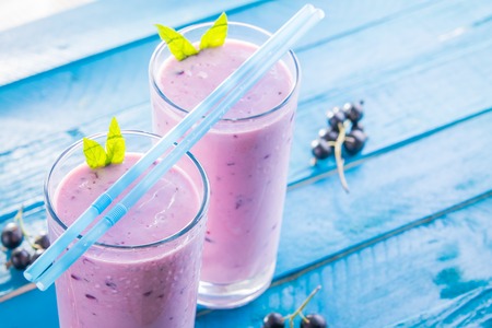 Fruity smoothie in glasses with black currant on blue wooden background. Healthy eating. Organic food.の写真素材