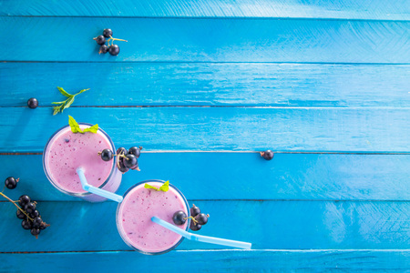 Fruity smoothie in glasses with black currant on blue wooden background. Healthy eating. Organic food.の写真素材