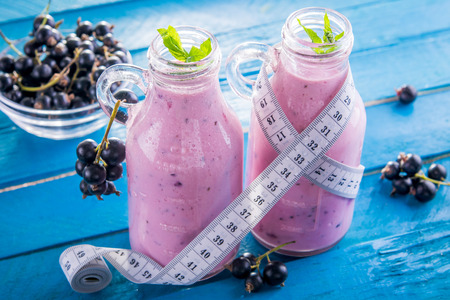 Fruity smoothie in glasses with black currant on blue wooden background. Diet concept. Healthy eating. Organic food.の写真素材