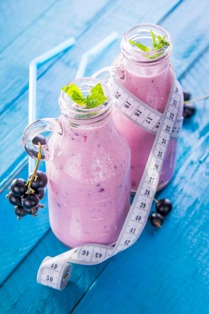 Fruity smoothie in glasses with black currant on blue wooden background. Diet concept. Healthy eating. Organic food.の写真素材