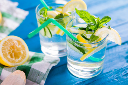 Refreshing lemonade of lemon, cucumber, lime and mint on blue background. Summer drink. Healthy organic drinksの写真素材