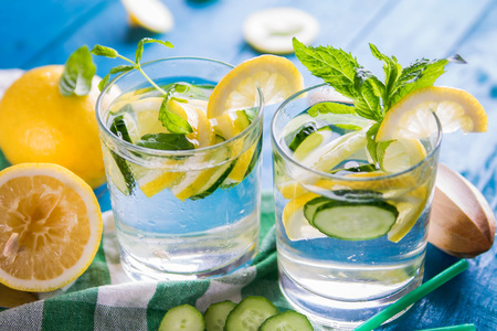 Refreshing lemonade of lemon, cucumber, lime and mint on blue background. Summer drink. Healthy organic drinksの写真素材