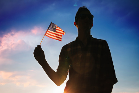 Man holding USA flag against the blue sky. Celebrating Independence Day of Americaの写真素材