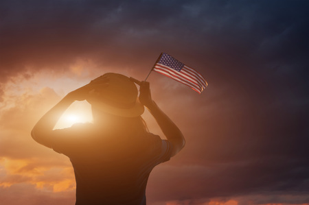 Woman holding USA flag against the blue sky. Celebrating Independence Day of Americaの写真素材