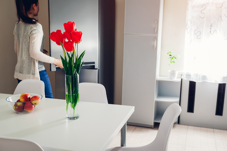 Woman cooking dinner in the kitchen. Young girl opens refrigerator to get some food. Modern kitchen design. Cozy apartmentの写真素材