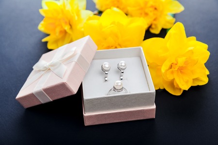 Set of pearl jewellery in gift box with flowers on black background. Silver earrings and ring with pearls as a present for Mother's day. Accessories and jewelry.の写真素材