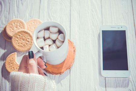 Drinking morning coffee with cookies online. Using smartphone while having breakfastの写真素材