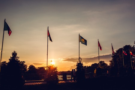 A row of flying flags of nations on sunset sky background in summer park. Unity of nations. Flags of different countries.の写真素材