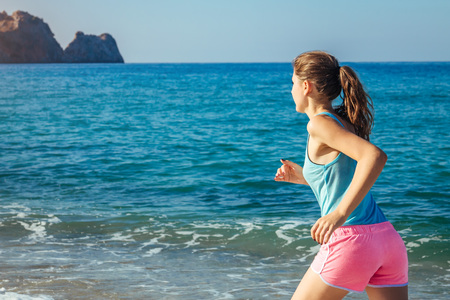 Young woman running on the beach in the morning. Healthy lifestyle. Sportive girl training by seaの写真素材