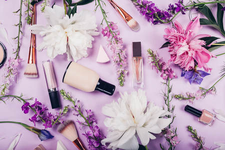 Set of natural cosmetics and brushes with fresh flowers on purple background. Organic cosmetics conceptの写真素材