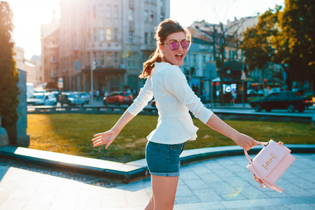 Young excited woman wearing stylish outfit outdoors. Happy girl jumping and having fun. Beauty fashion modelの写真素材