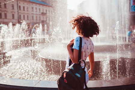 Happy young woman running and dancing by fountain on summer street. Hipster teen girl having funの写真素材