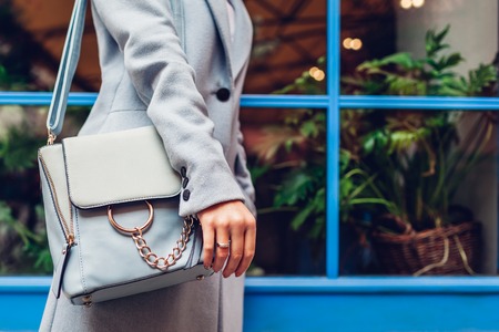Close-up of blue female handbag. Woman holding leather bag outdoors. Fashionable accessories and clothesの写真素材